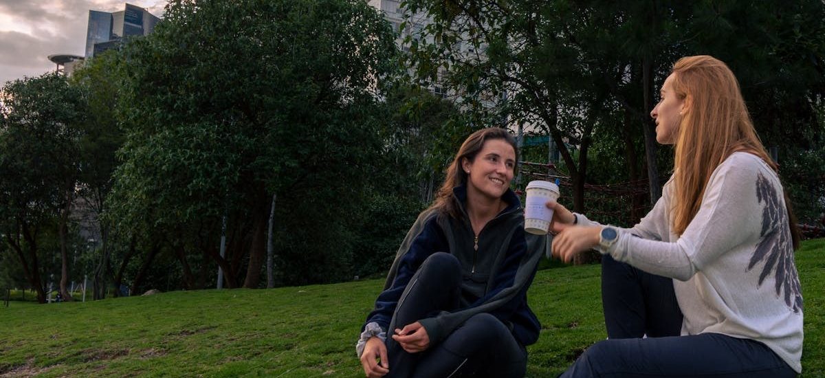 Two women enjoying coffee and conversation in a vibrant park setting in Mexico City.