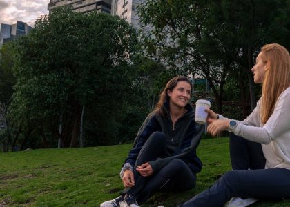 Two women enjoying coffee and conversation in a vibrant park setting in Mexico City.